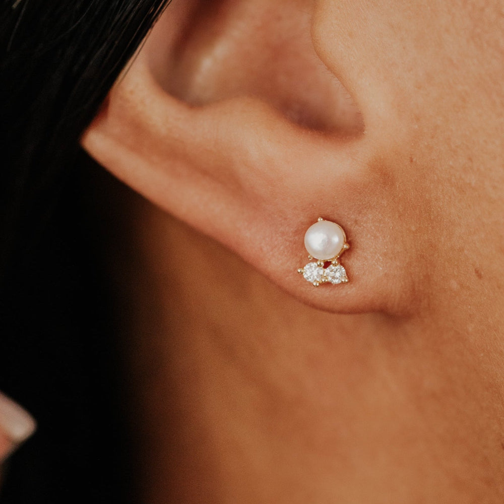Close-up of an ear wearing a pearl earring with small diamonds.
