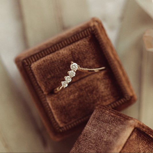A diamond band-style tracer ring with tapering diamonds on one side, presented in a brown velvet box with a white ribbon.