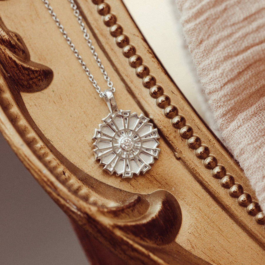 Silver necklace with a sunflower pendant on a textured surface