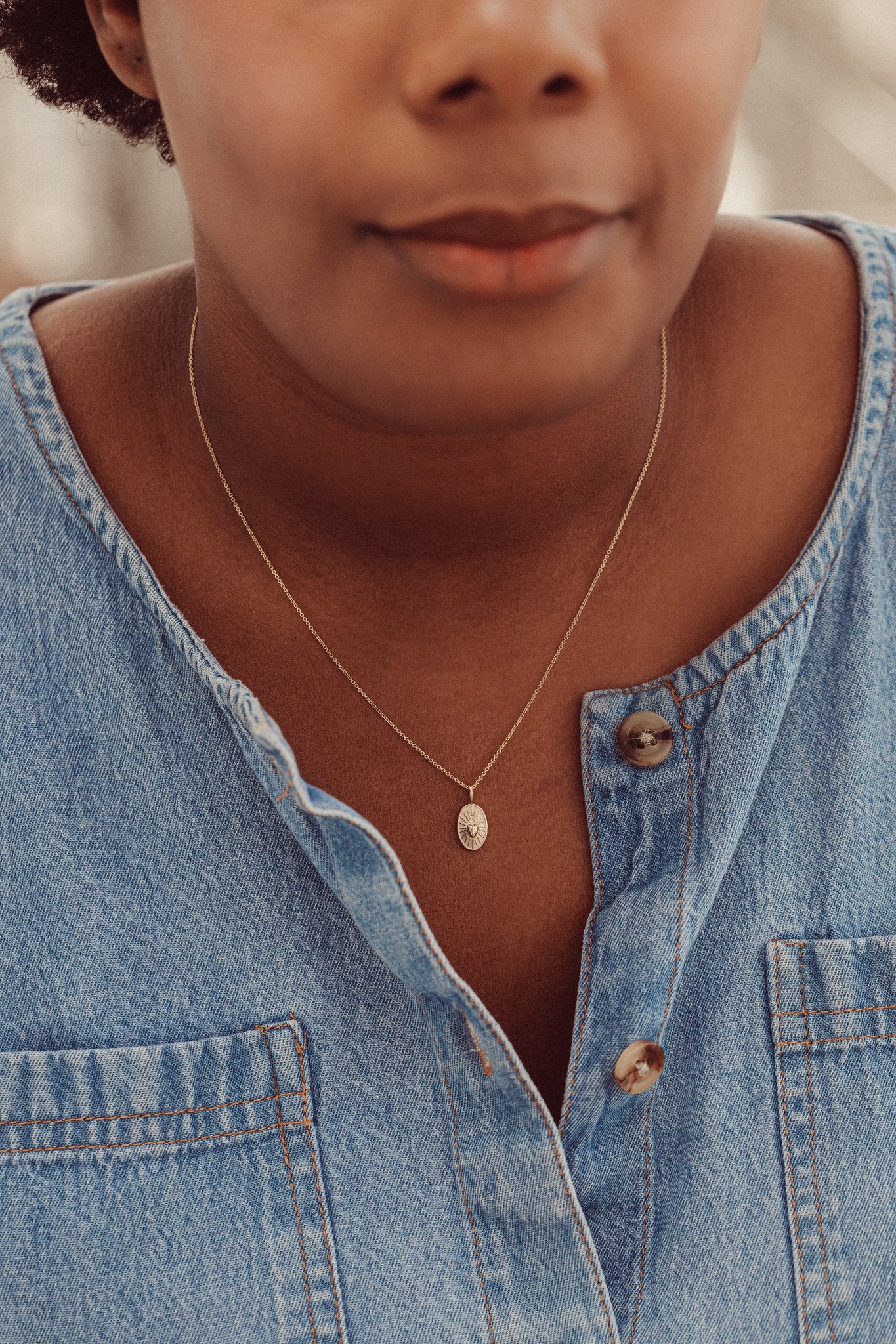 Gold necklace with a heart charm on a models neck