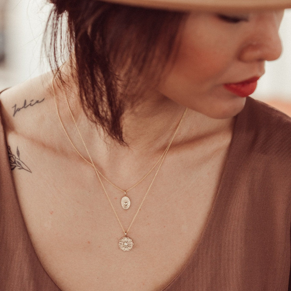 Person wearing a brown hat and multiple gold necklaces with a blurred background