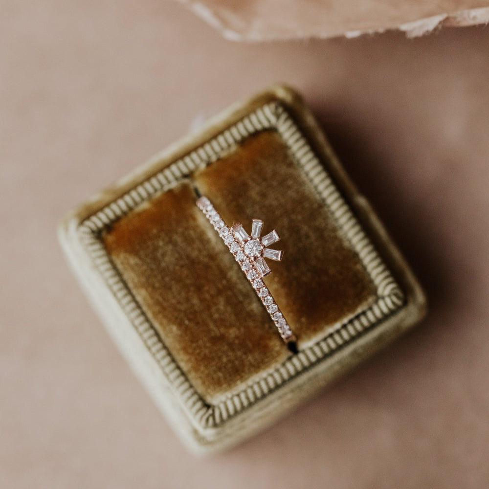 Diamond wedding band in a brown velvet box on a beige background.