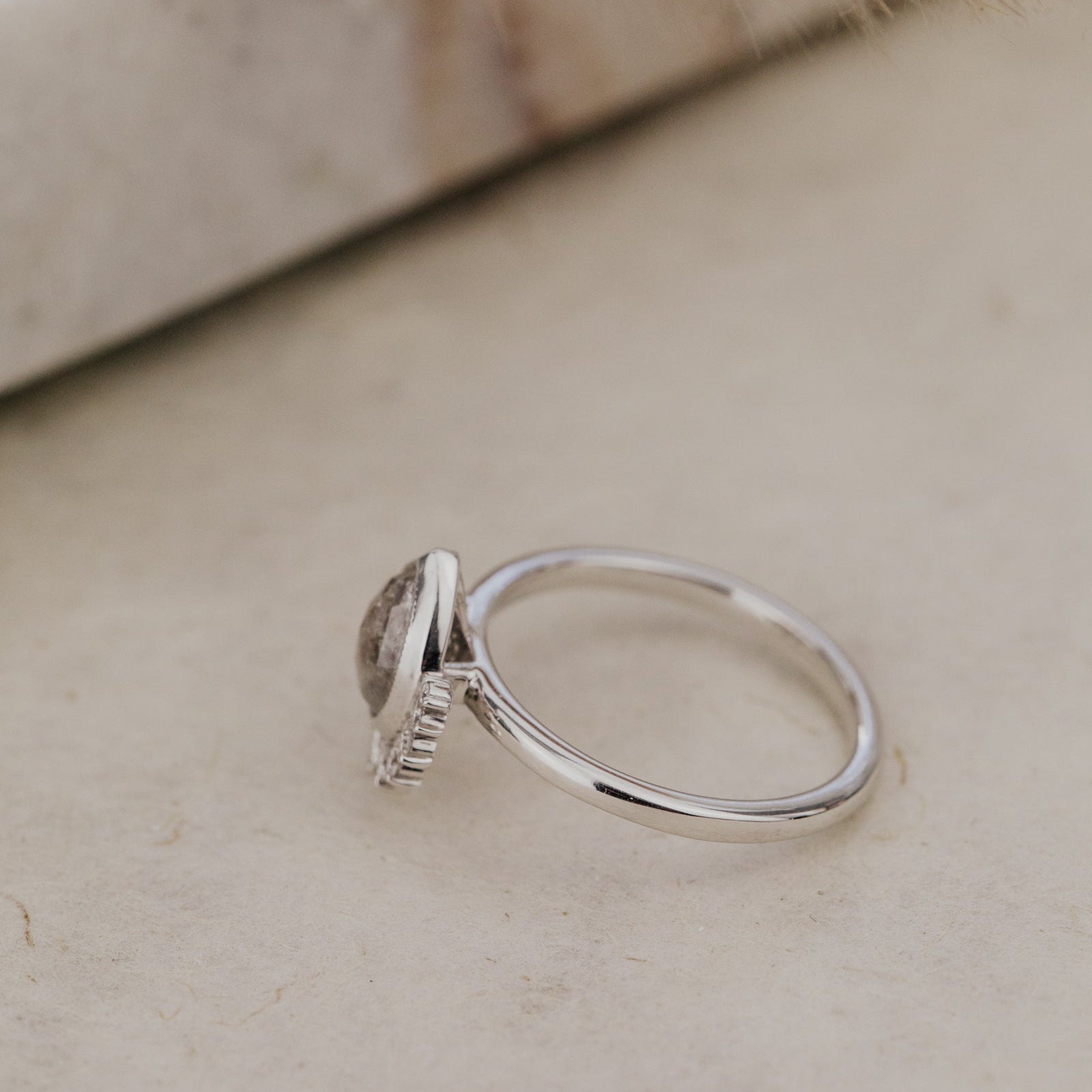 White Gold ring with a rustic diamond on a light surface with dried pampas grass.
