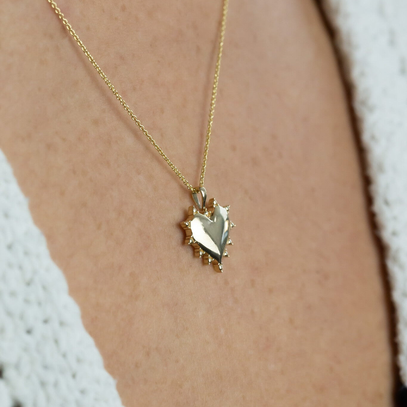 Gold necklace with a heart-shaped pendant on a person's neck