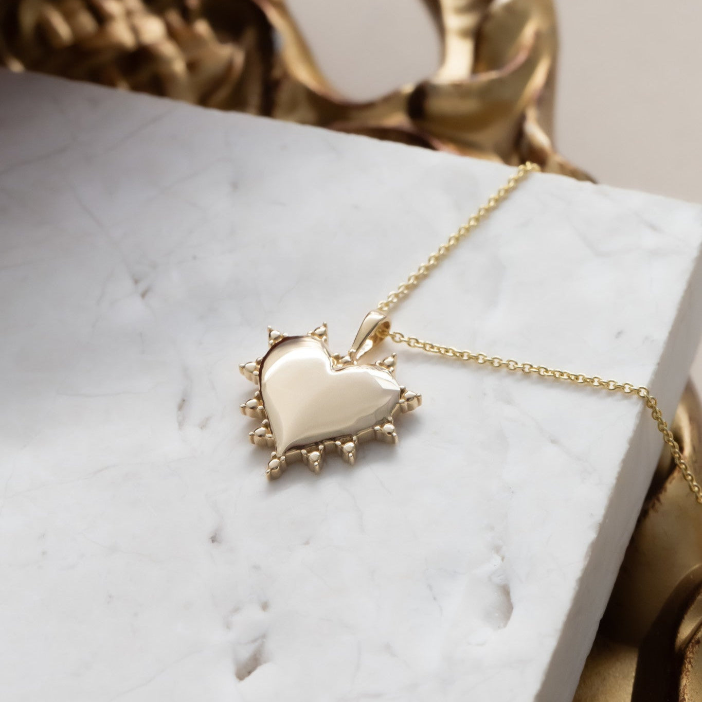 Gold heart-shaped necklace on a marble surface