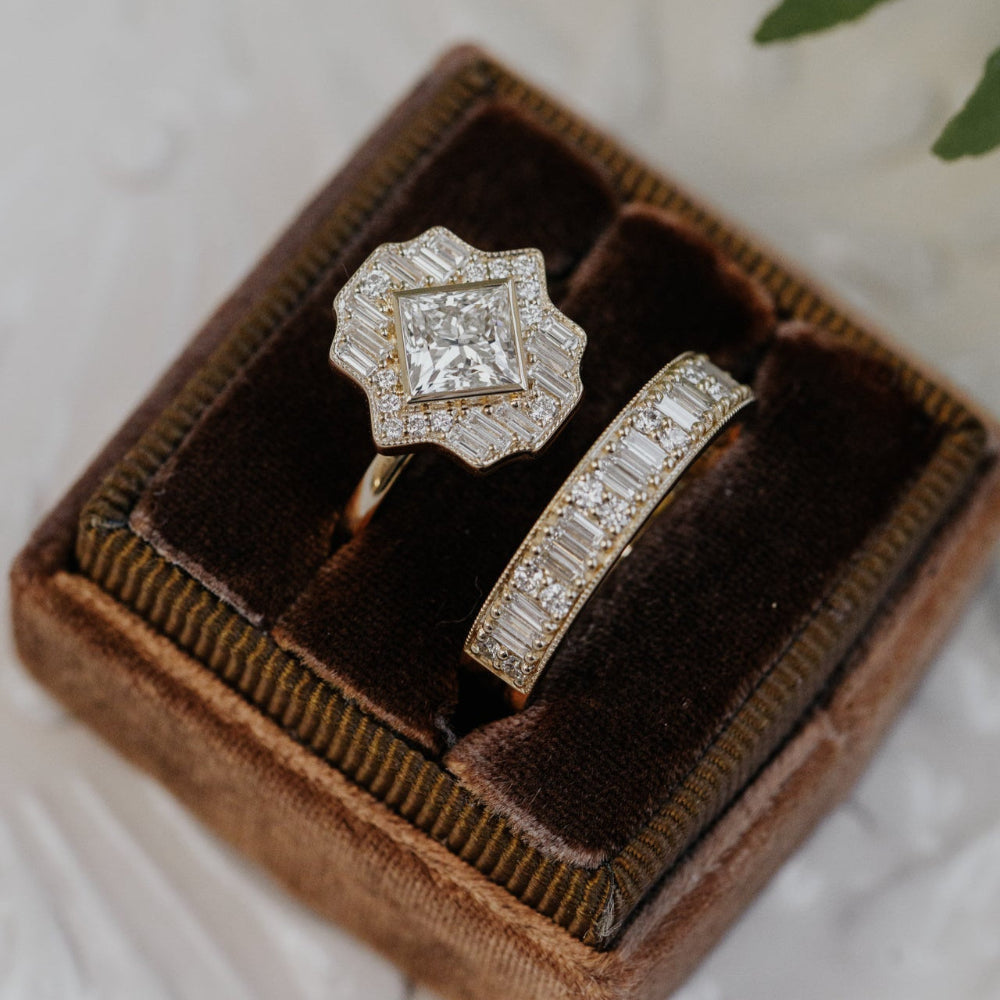  A diamond halo ring with a diamond band in a brown velvet box on a light background