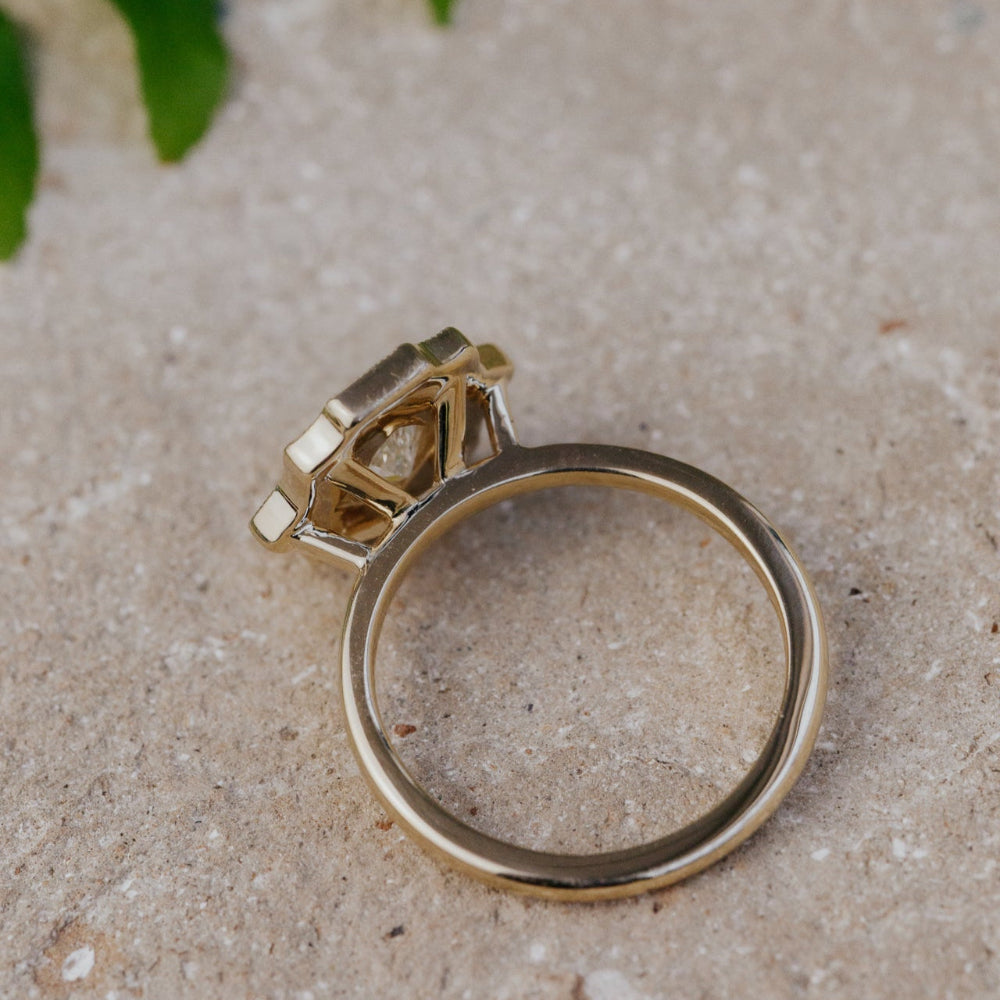 Gold ring with a diamond on a textured beige surface