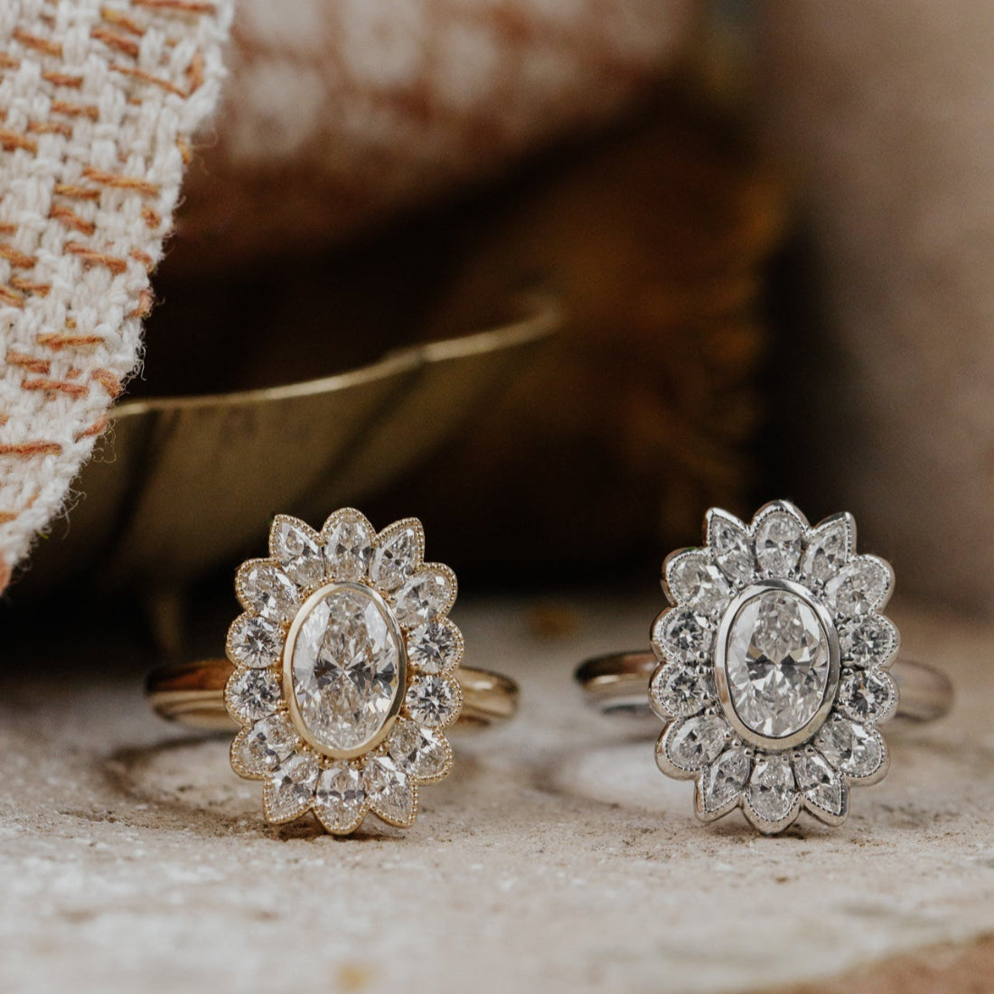 Two diamond rings with a halo on a textured surface.