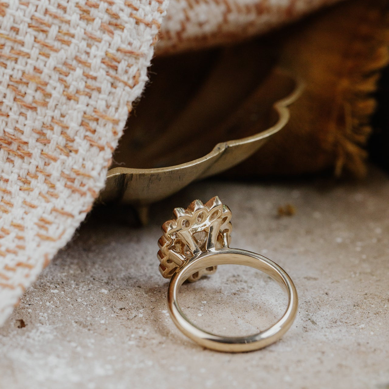 Gold diamond ring on a textured surface with fabric in the background