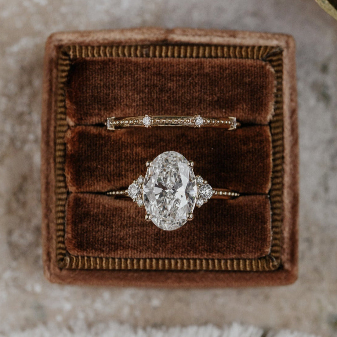 Diamond ring in a brown velvet box on a textured surface
