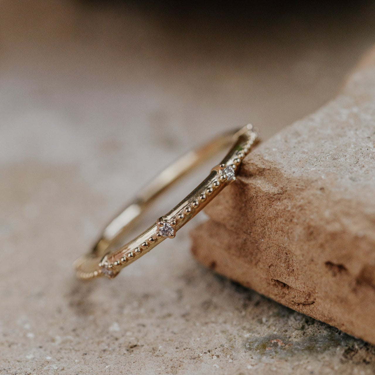 Gold band with small diamonds on a textured surface