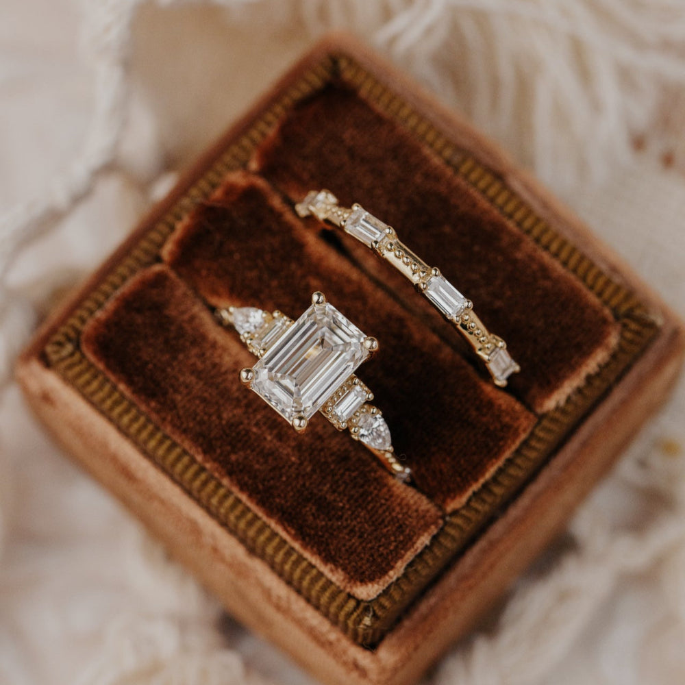 Two diamond rings in a brown velvet box on a soft fabric background