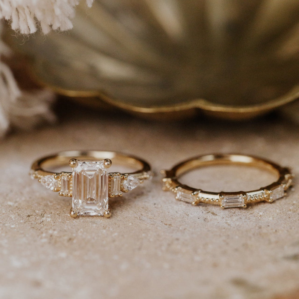 Two gold rings with diamond accents on a textured surface.