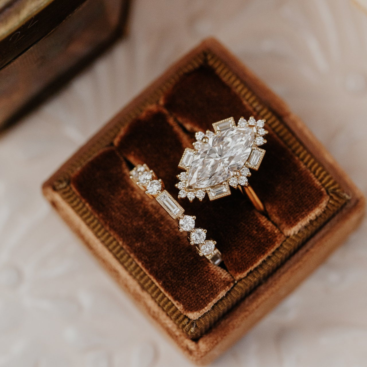 Diamond band and ring in a brown velvet box on a marble surface