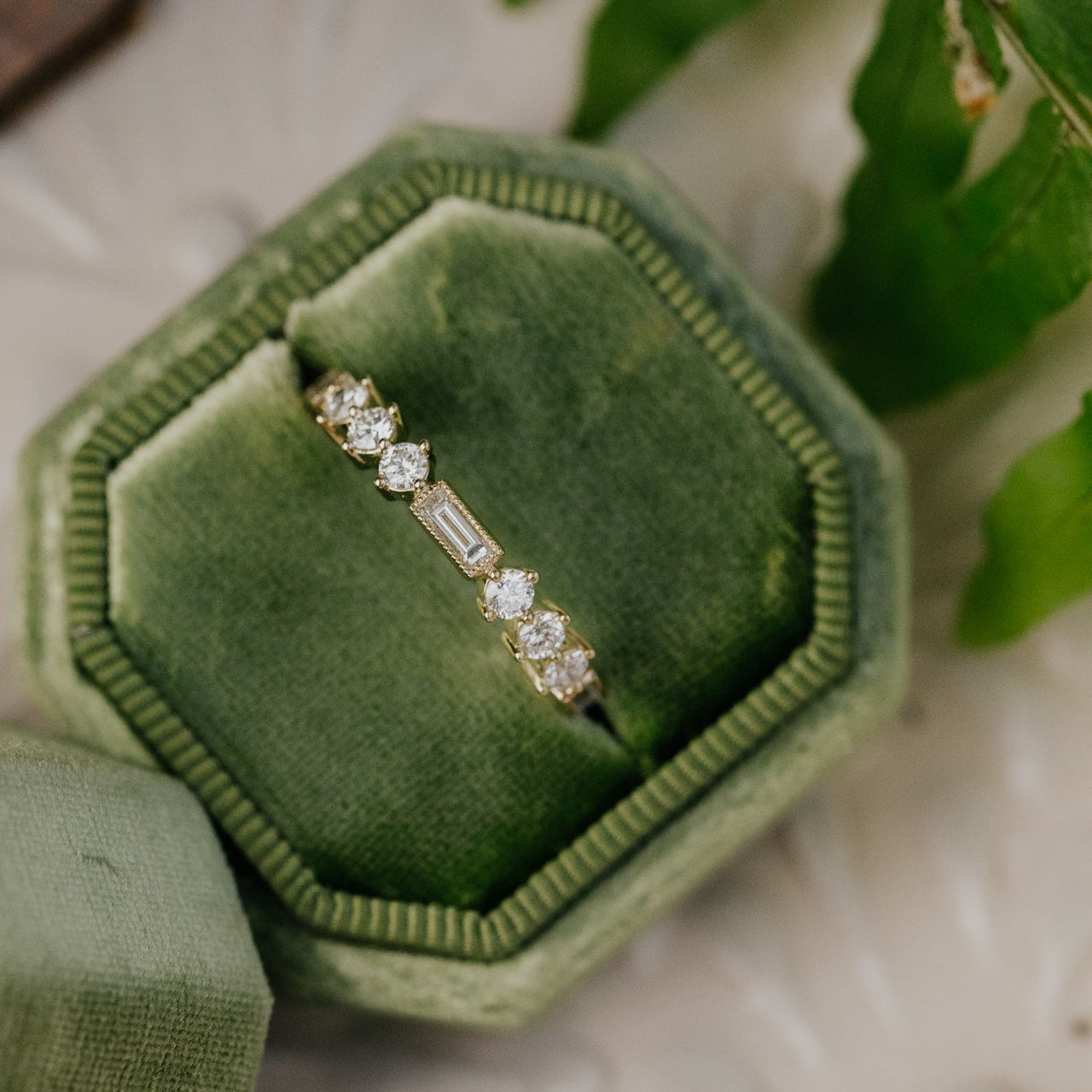 Diamond band in a green velvet box with fern leaves in the background