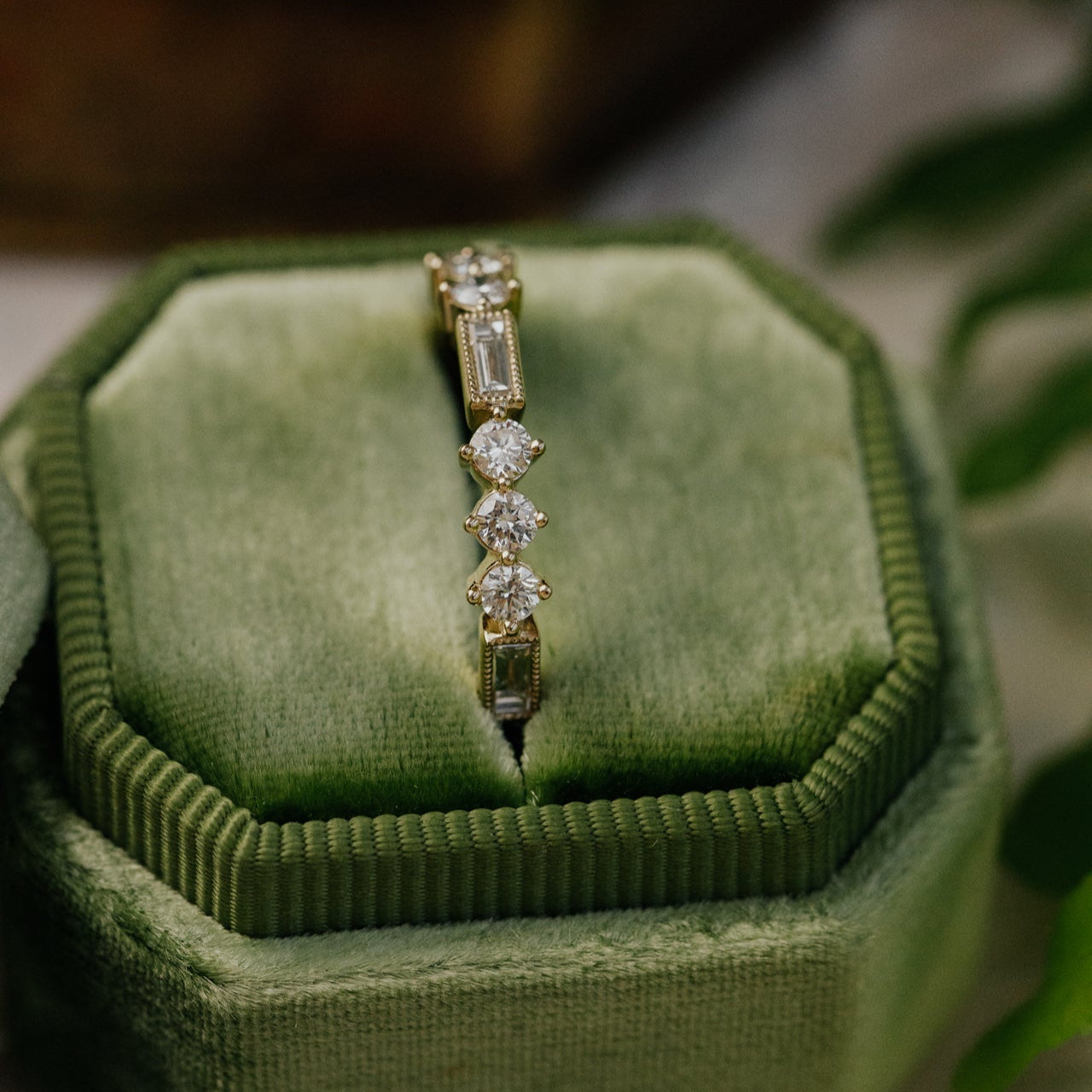 Gold ring with diamonds on a green velvet cushion