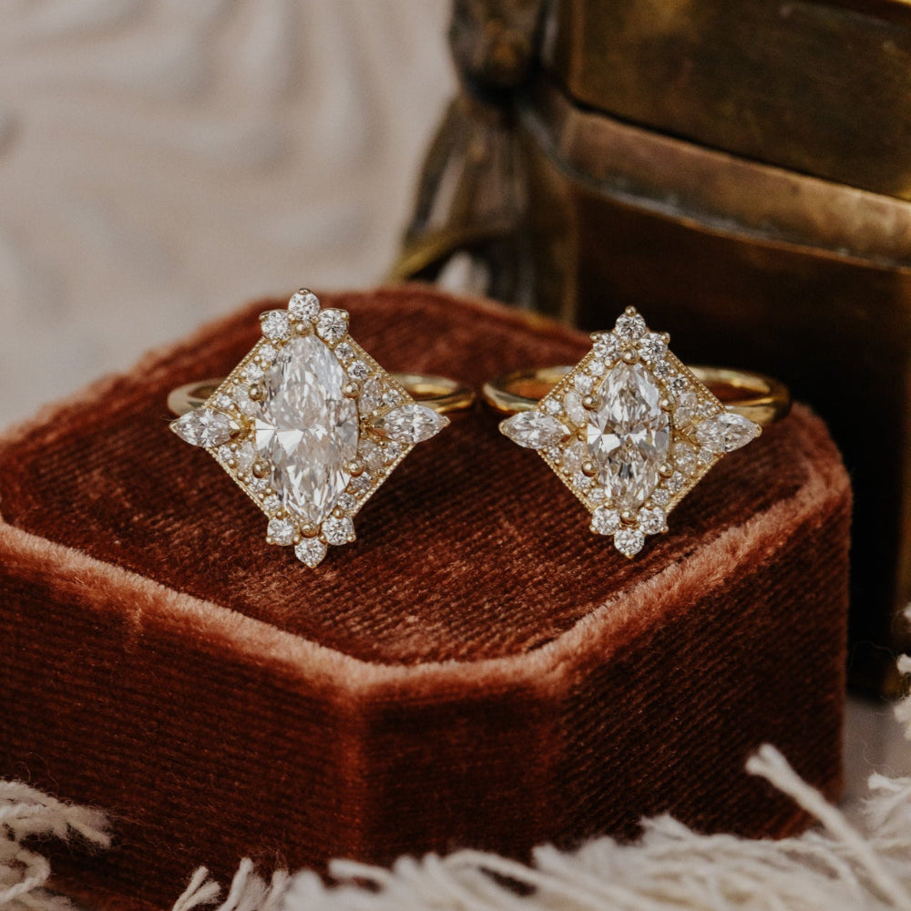 Pair of diamond halo rings  on a brown velvet cushion with a textured surface in the background.