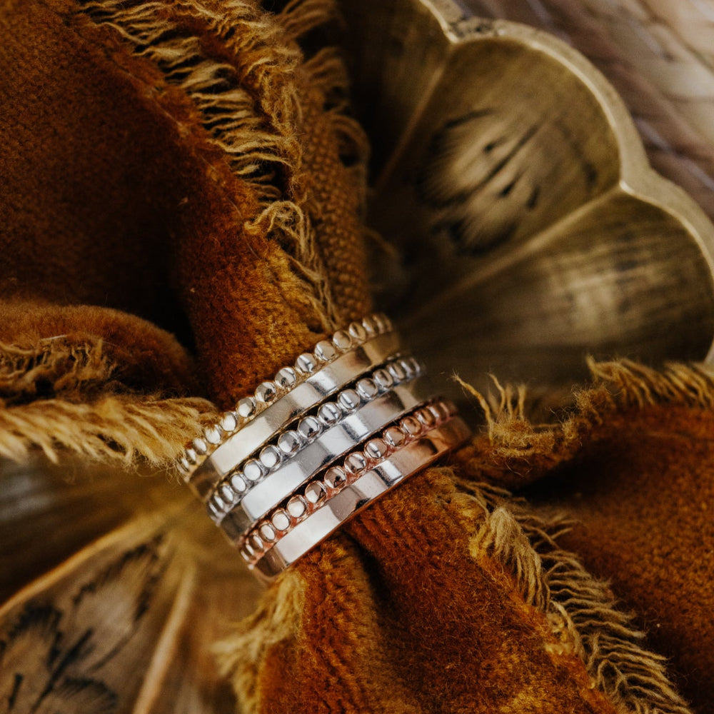 Close-up of a decorative napkin ring with three gold bands on a textured fabric background