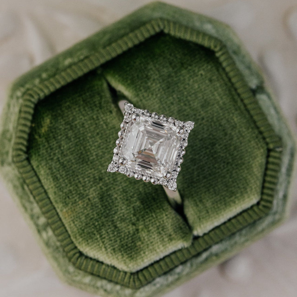 Asscher cut diamond ring in a green velvet box with leaves in the background