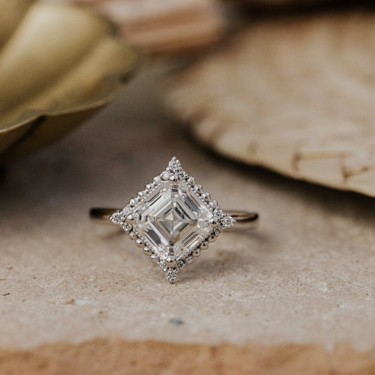 Diamond ring with a square-cut center stone on a textured surface