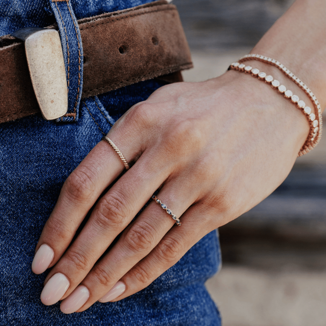 A 14k gold ring featuring blue marquise sapphire gemstones displayed on the ring finger of a hand model. 