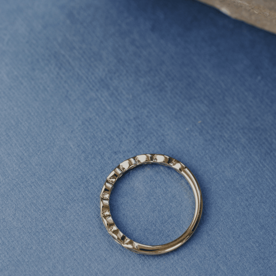 A 14k gold ring featuring blue marquise sapphire gemstones from an arial POV displayed on a blue surface with a soft-focus background.