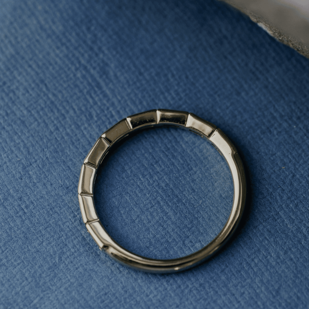 A 14k gold ring featuring blue oval sapphire gemstones from an ariel POV displayed on a white surface with a soft-focus background.