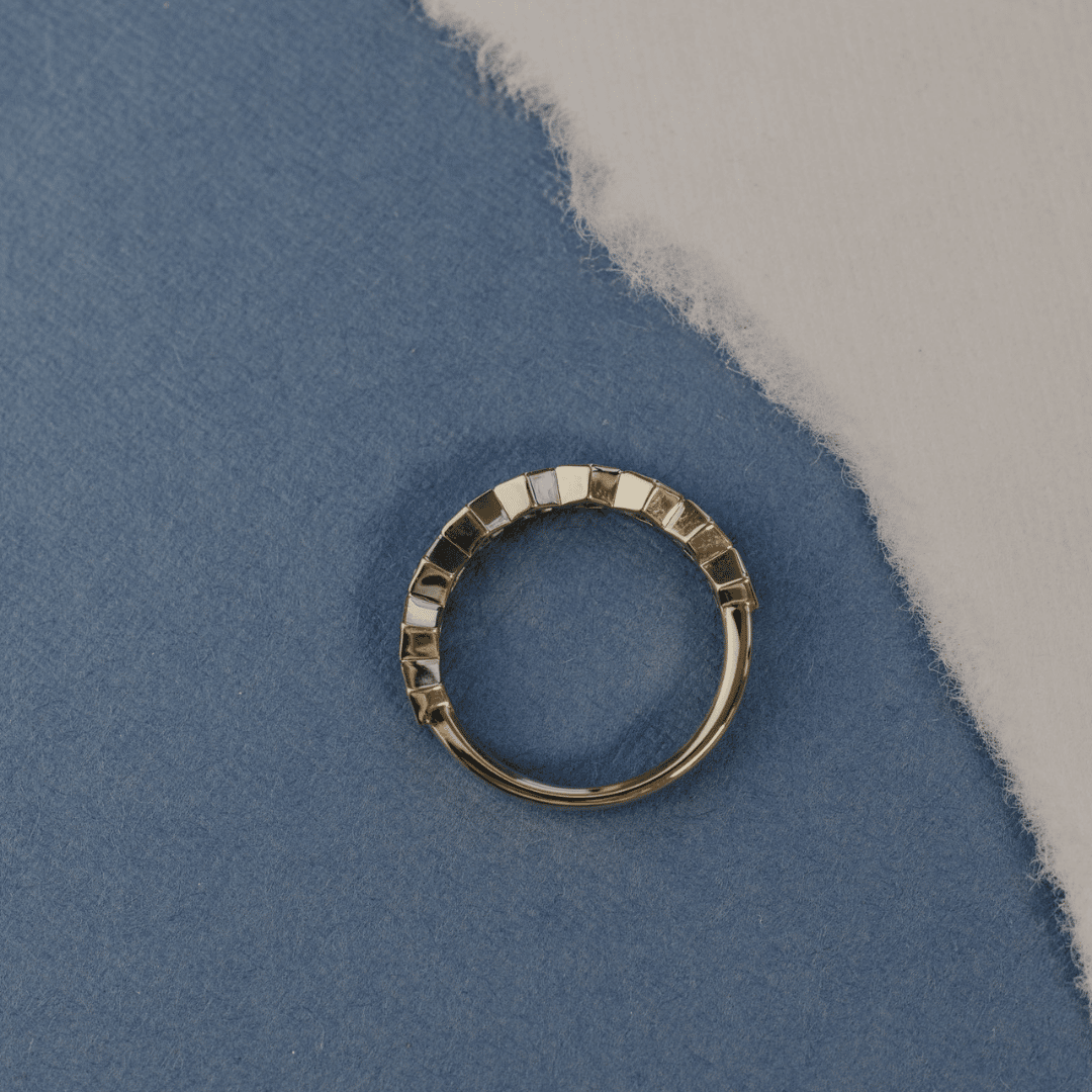 A 14k gold ring featuring blue hexagonal cut sapphire gemstones from an ariel POV, displayed on a white surface with a soft-focus background.