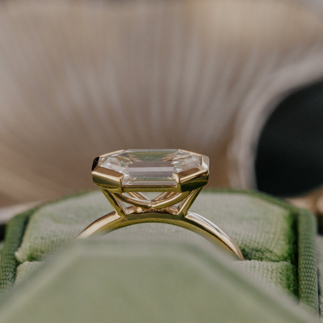 Gold ring with a large lab grown diamond on a green cushion.