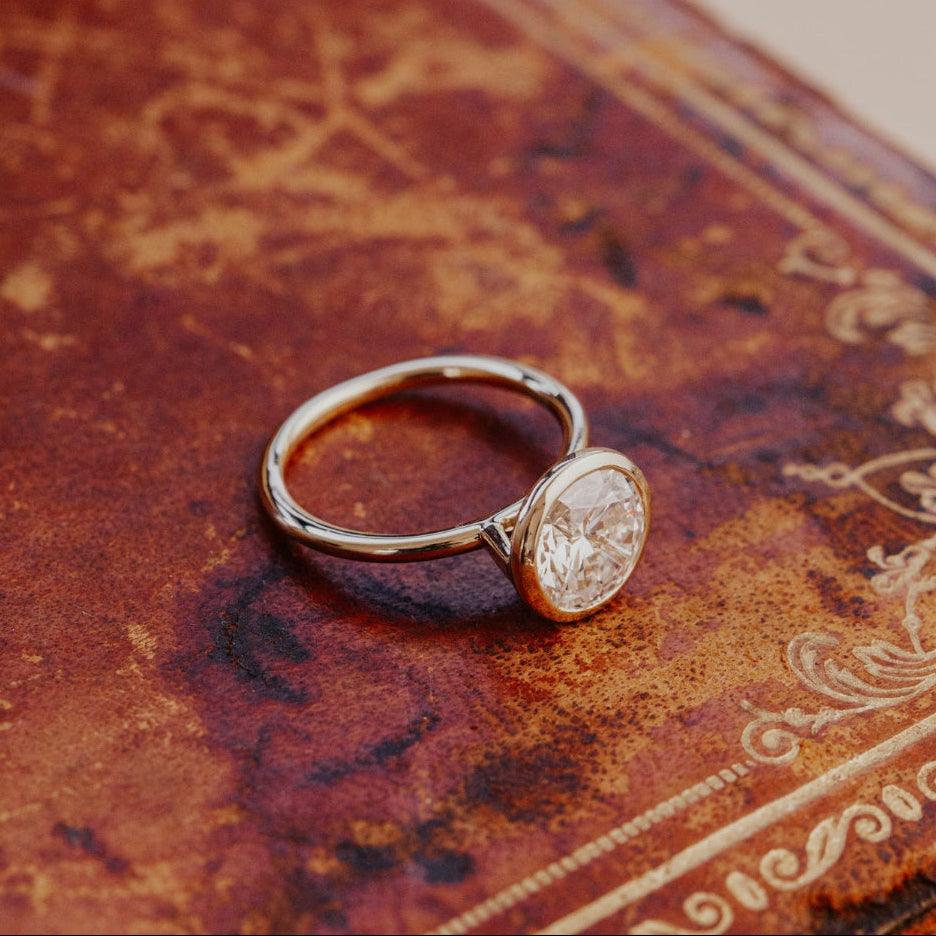 The Bailey bezel set ring with a round diamond on an ornate book.