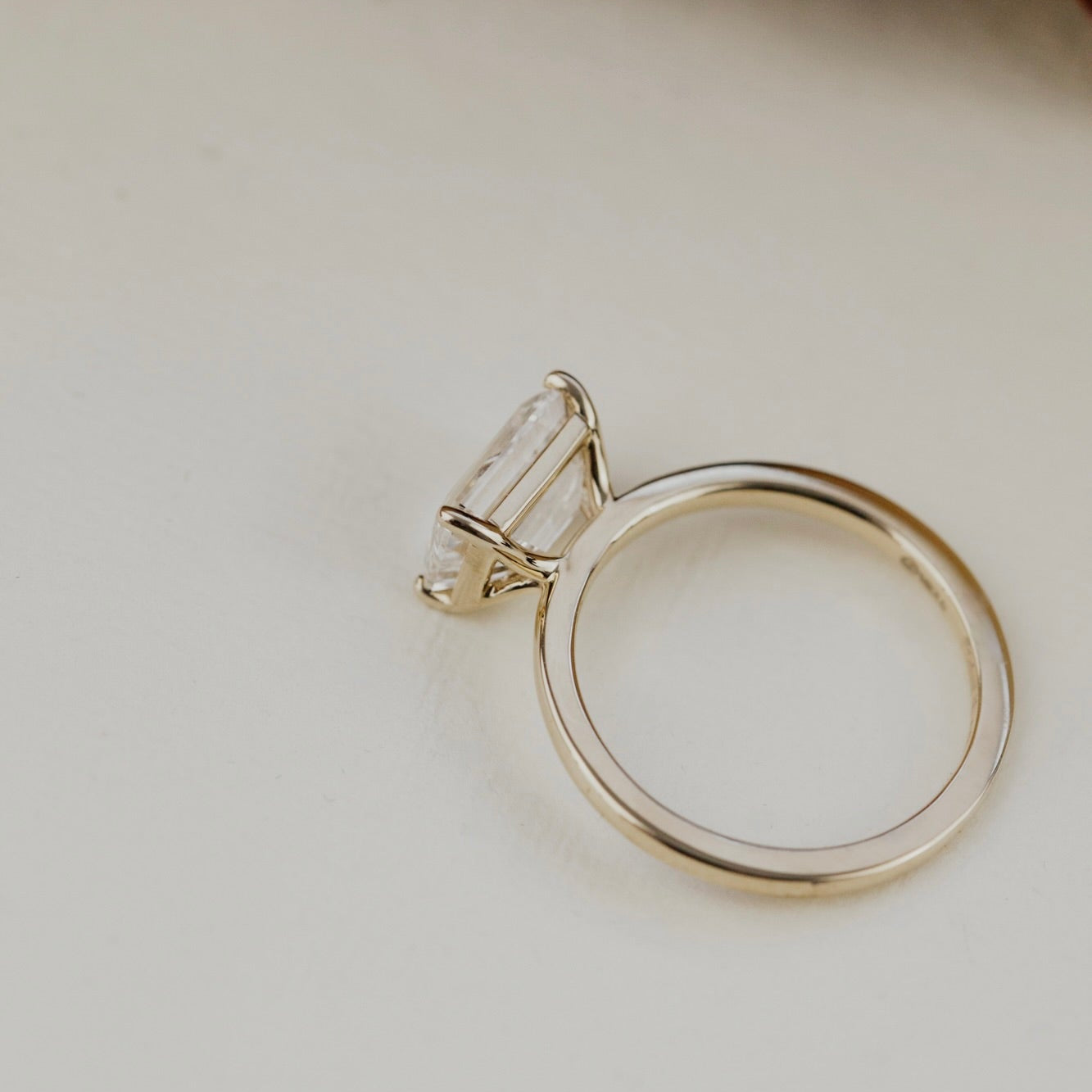 The Bennett emerald cut solitaire diamond ring on a light background.