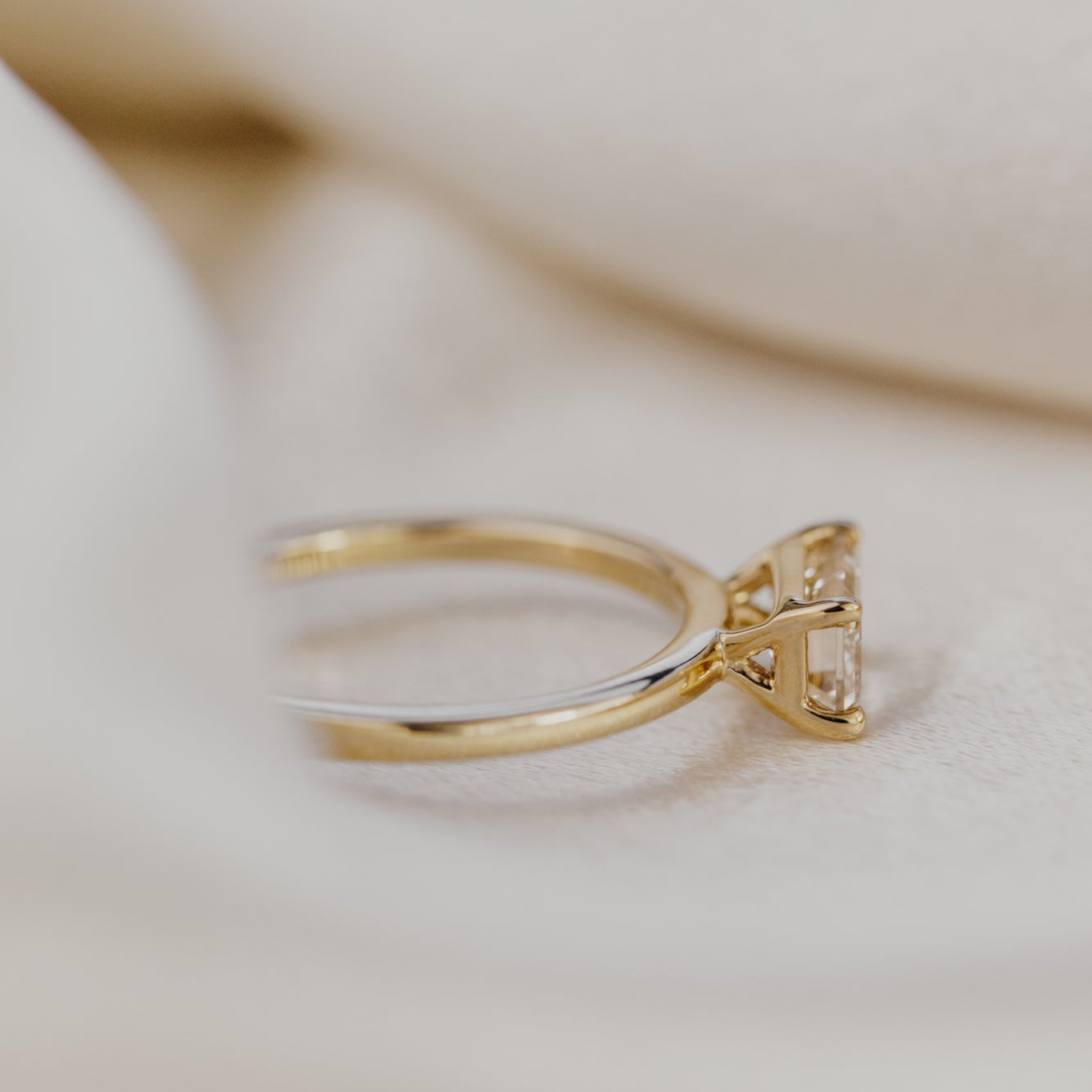 Gold engagement ring with a champagne diamond on a light background.