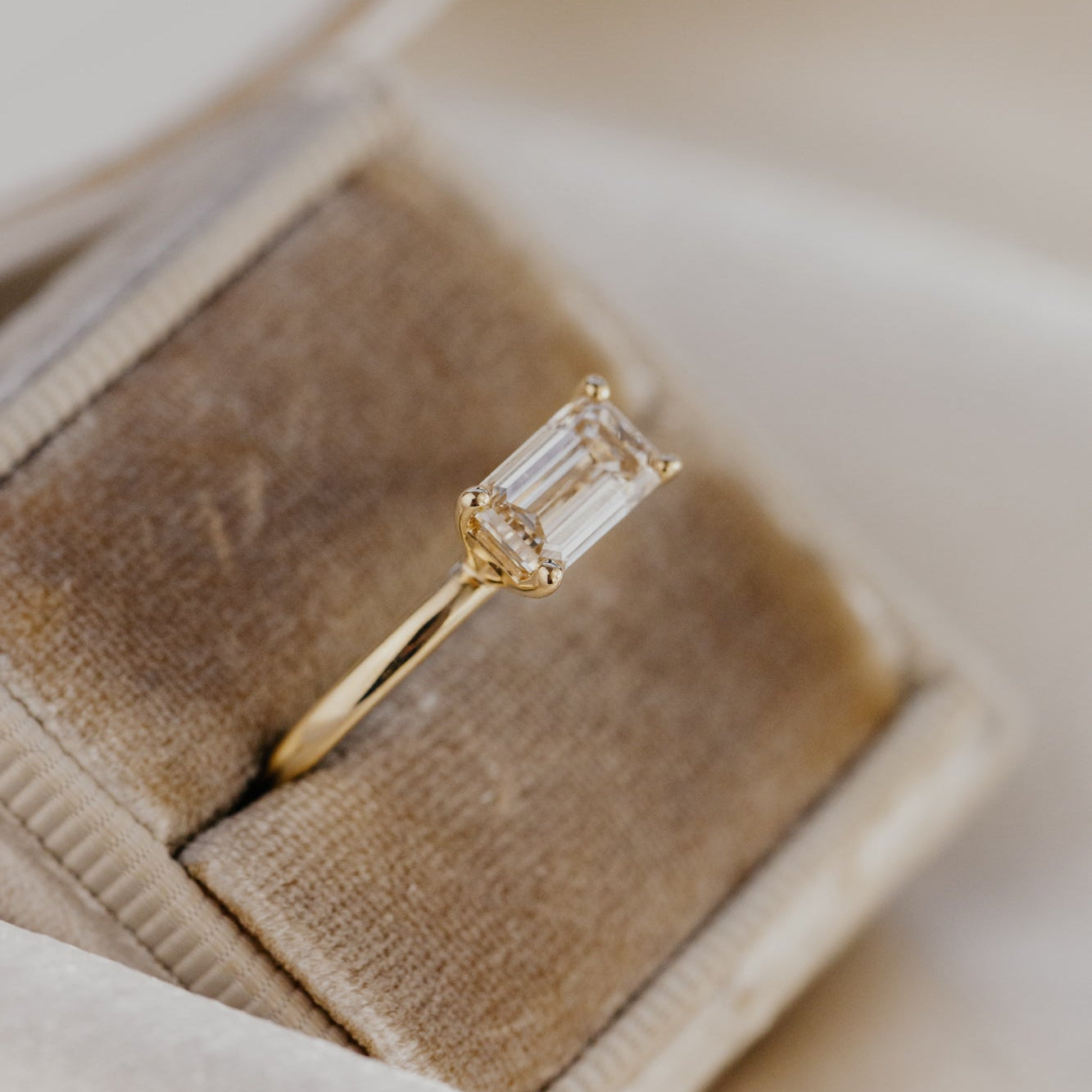 Gold engagement ring with a champagne diamond in a brown velvet box.