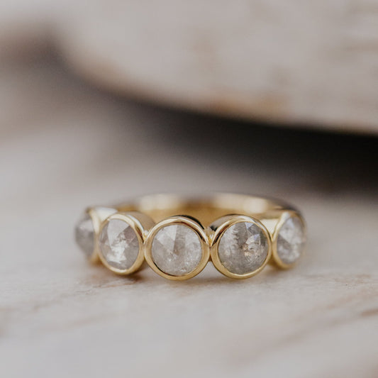 Gold Blaine ring with five round rustic diamonds on a neutral background.