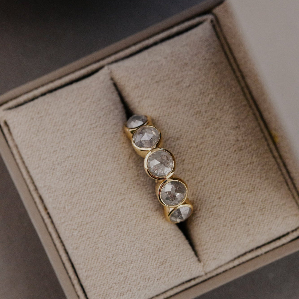 Gold Blaine ring with five round bezel-set rustic diamonds on a textured box.