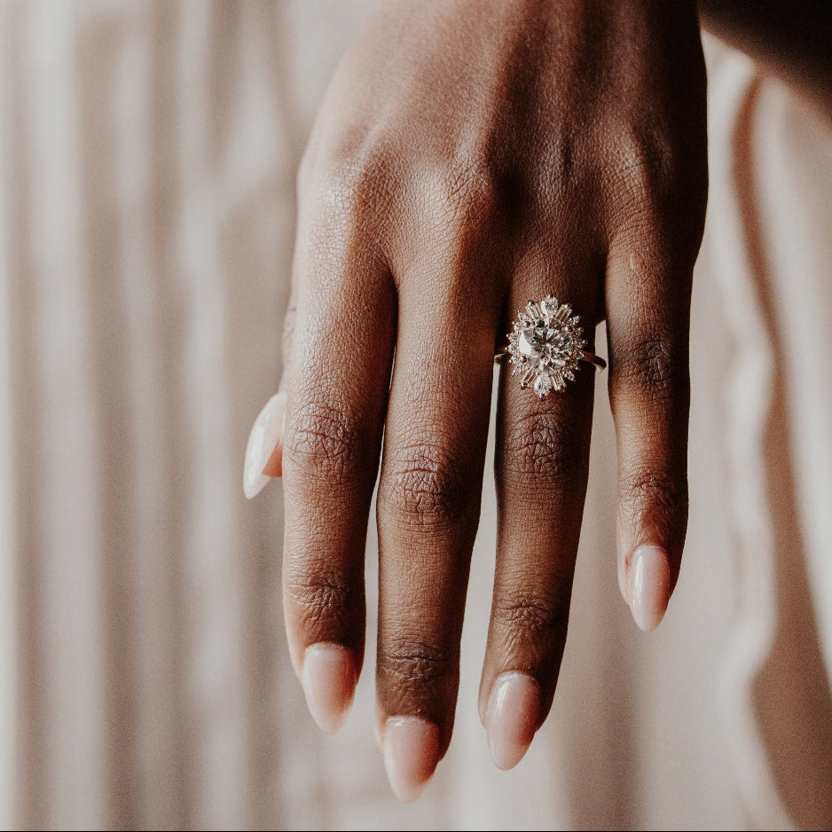 Close up of a model wearing a round diamond engagement ring with a diamond halo