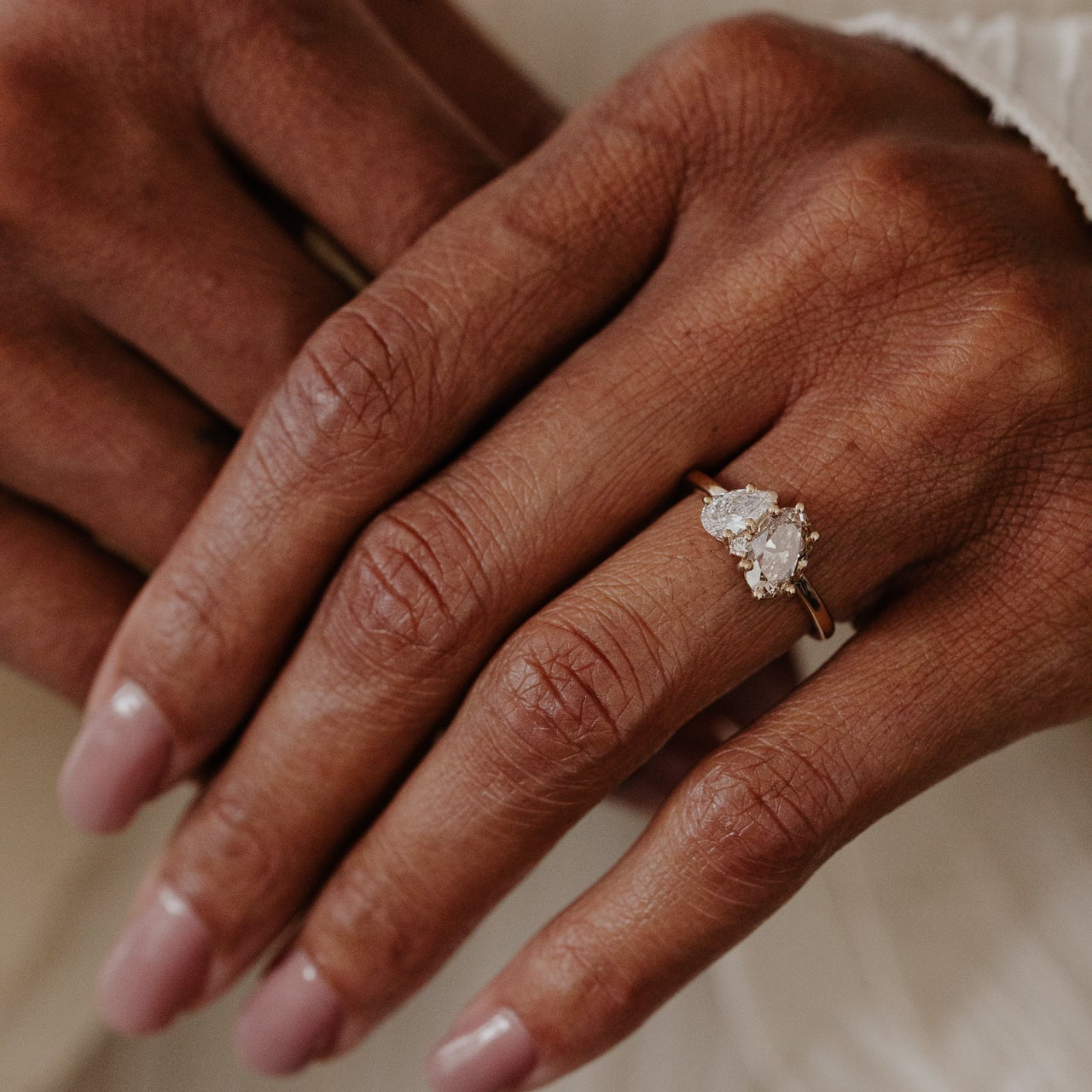 Close-up of a hand wearing a champagne and lab grown diamond toi et moi ring with a blurred background.