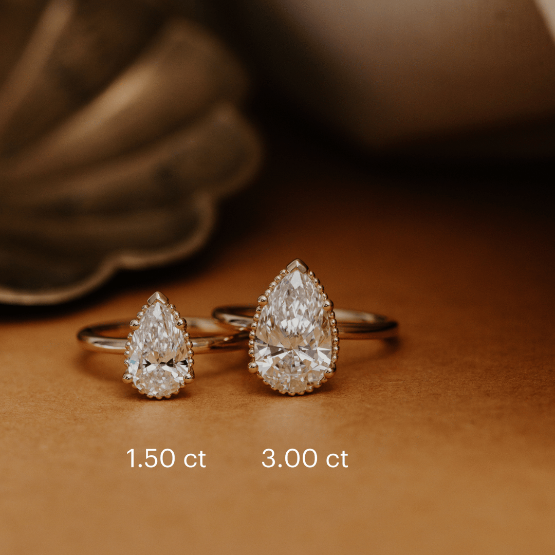 Two Charlotte pear diamond engagement ring in different carat weights with a size chart.