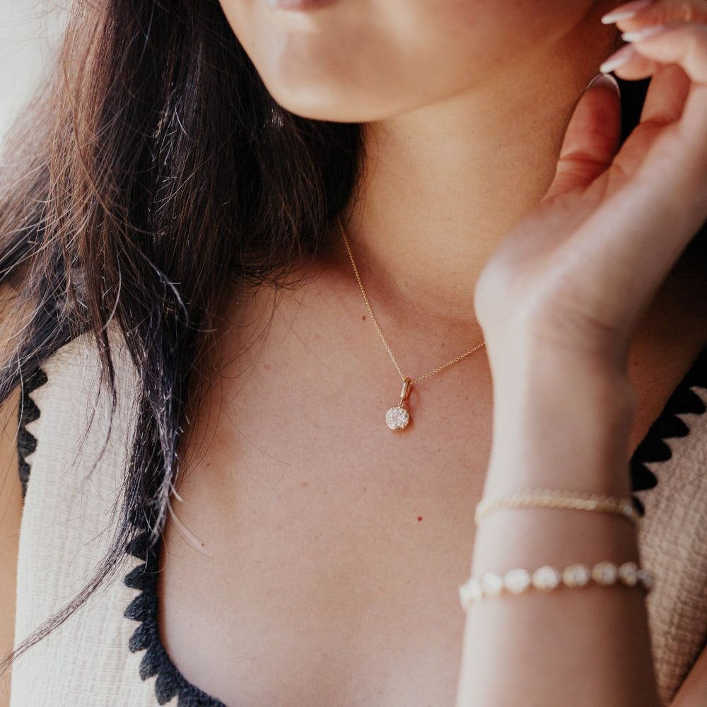 Close-up of a person wearing jewelry including earrings, necklace, and bracelet.