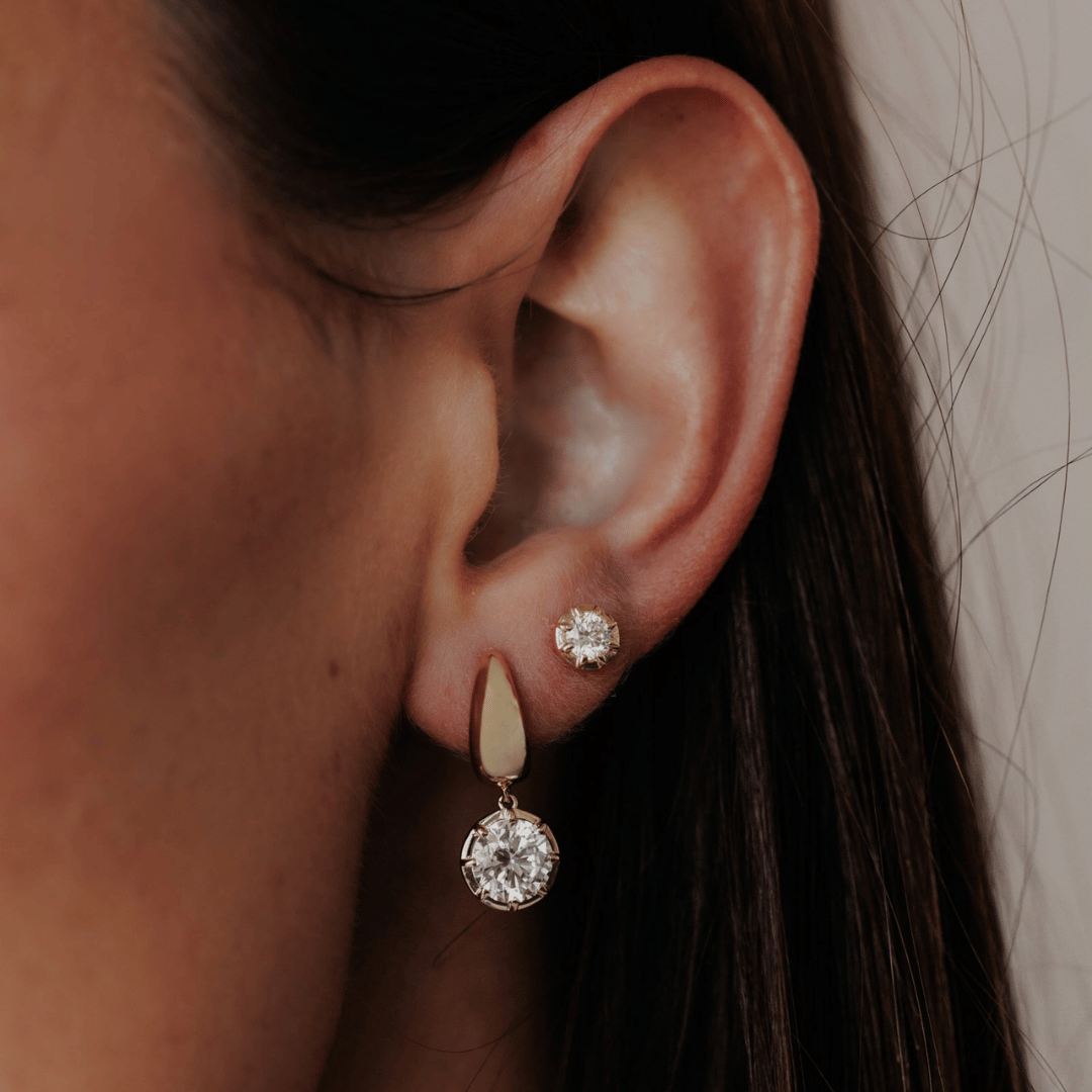14k gold round cut, lab grown diamond dangle hoop earrings showcased on the ear of a model. 