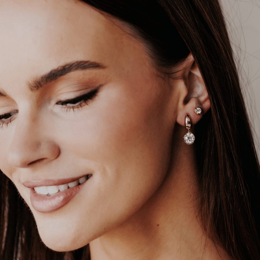 14k gold round cut, lab grown diamond dangle hoop earrings showcased on the ear of a model.  
