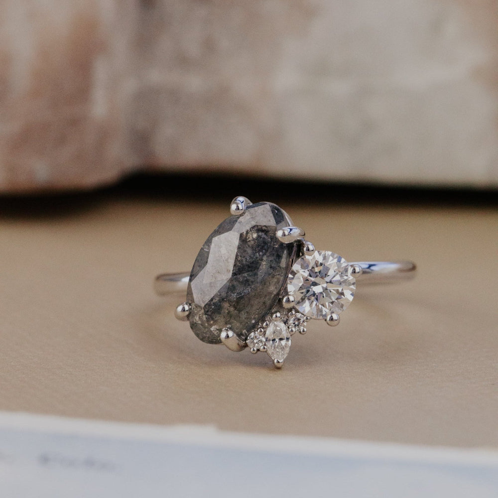 White gold ring with a large galaxy diamon dand smaller diamonds on a textured surface.