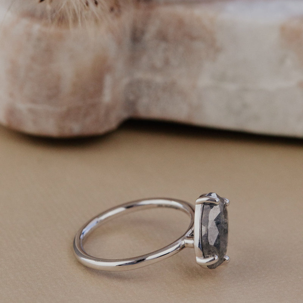 White gold ring with a galaxy diamond on a beige surface.