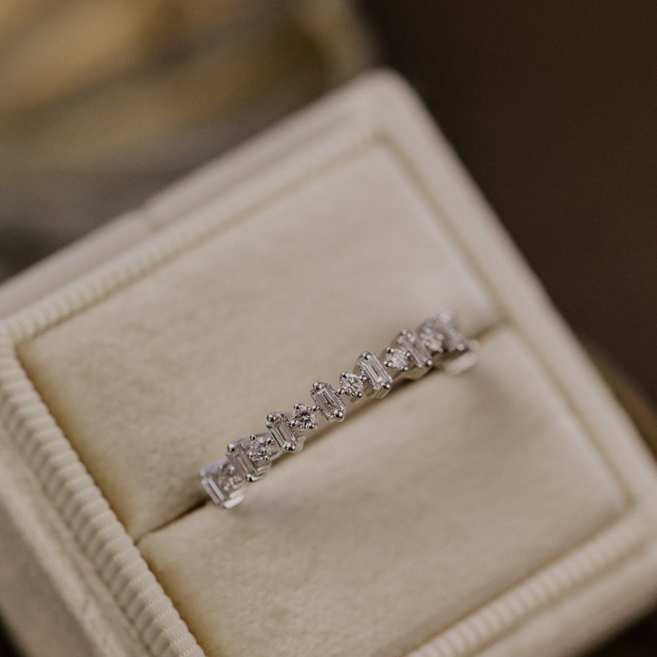 Diamond wedding band in a jewelry box with a blurred background.