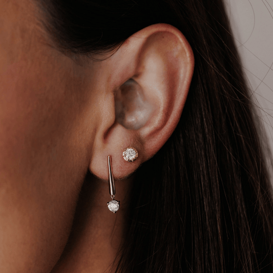 14k gold, long bar diamond earrings showcased on the ear of a model. 
