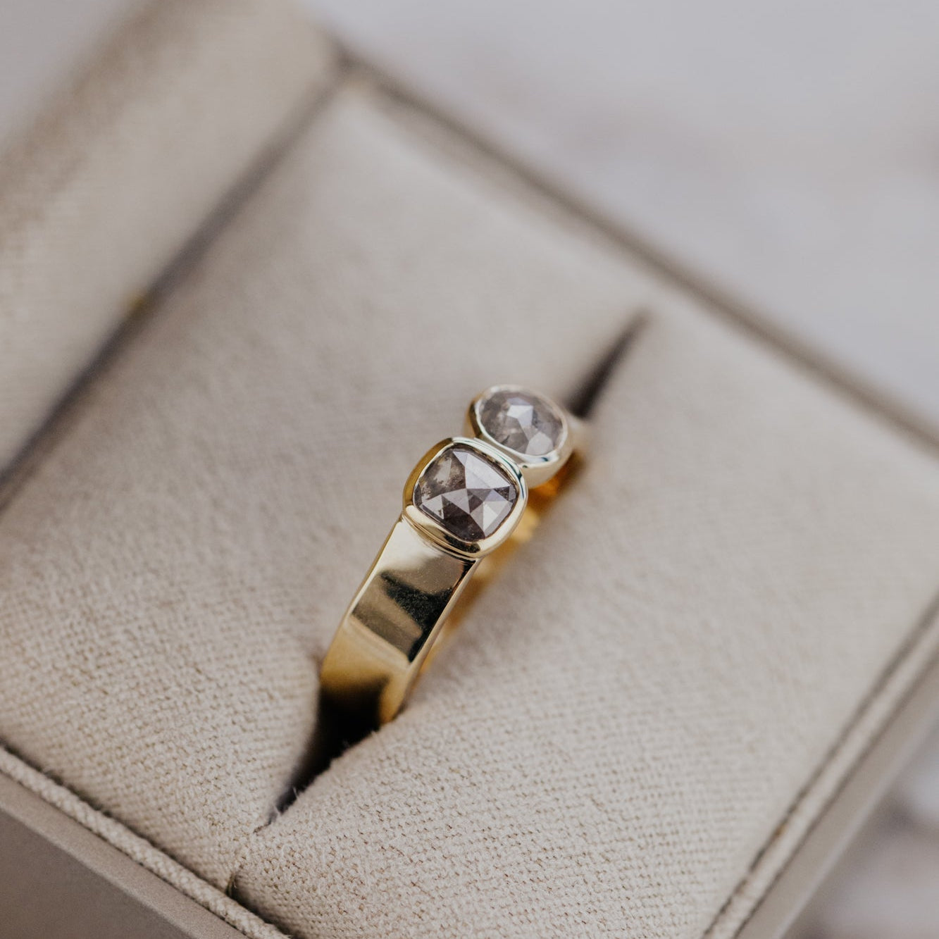 Gold ring with two rustic diamonds in a jewelry box.