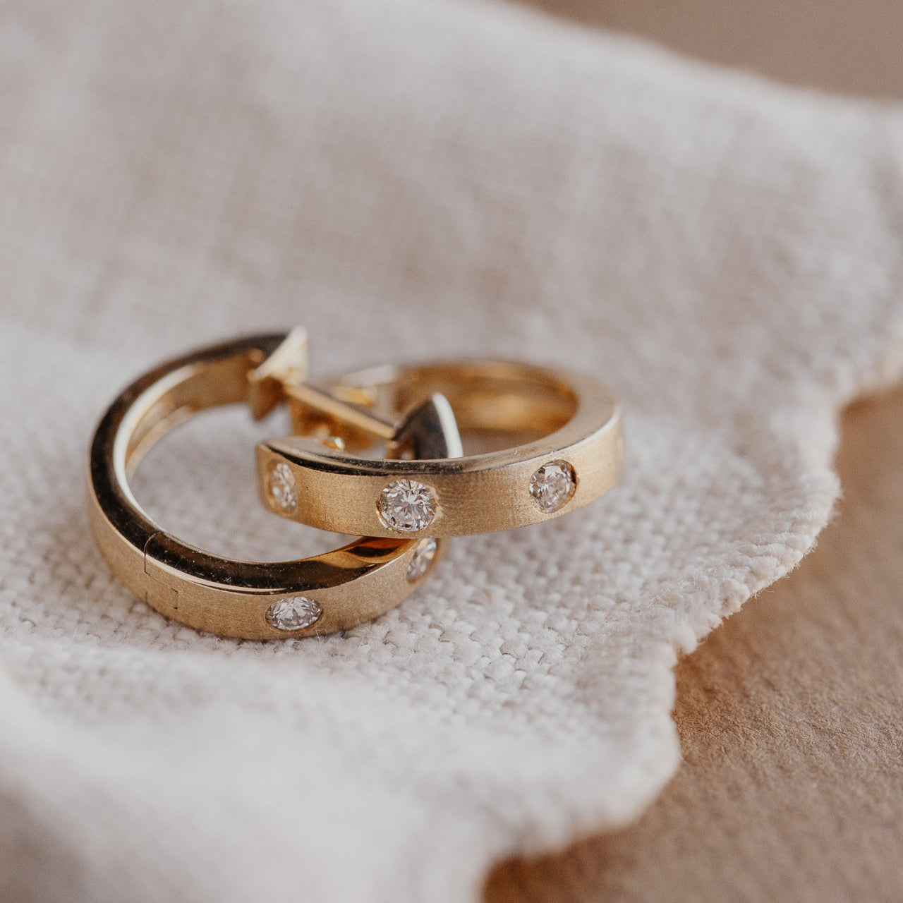 Three Hammer Set Round Diamonds on Hoop Earrings in 14k yellow gold clasped together