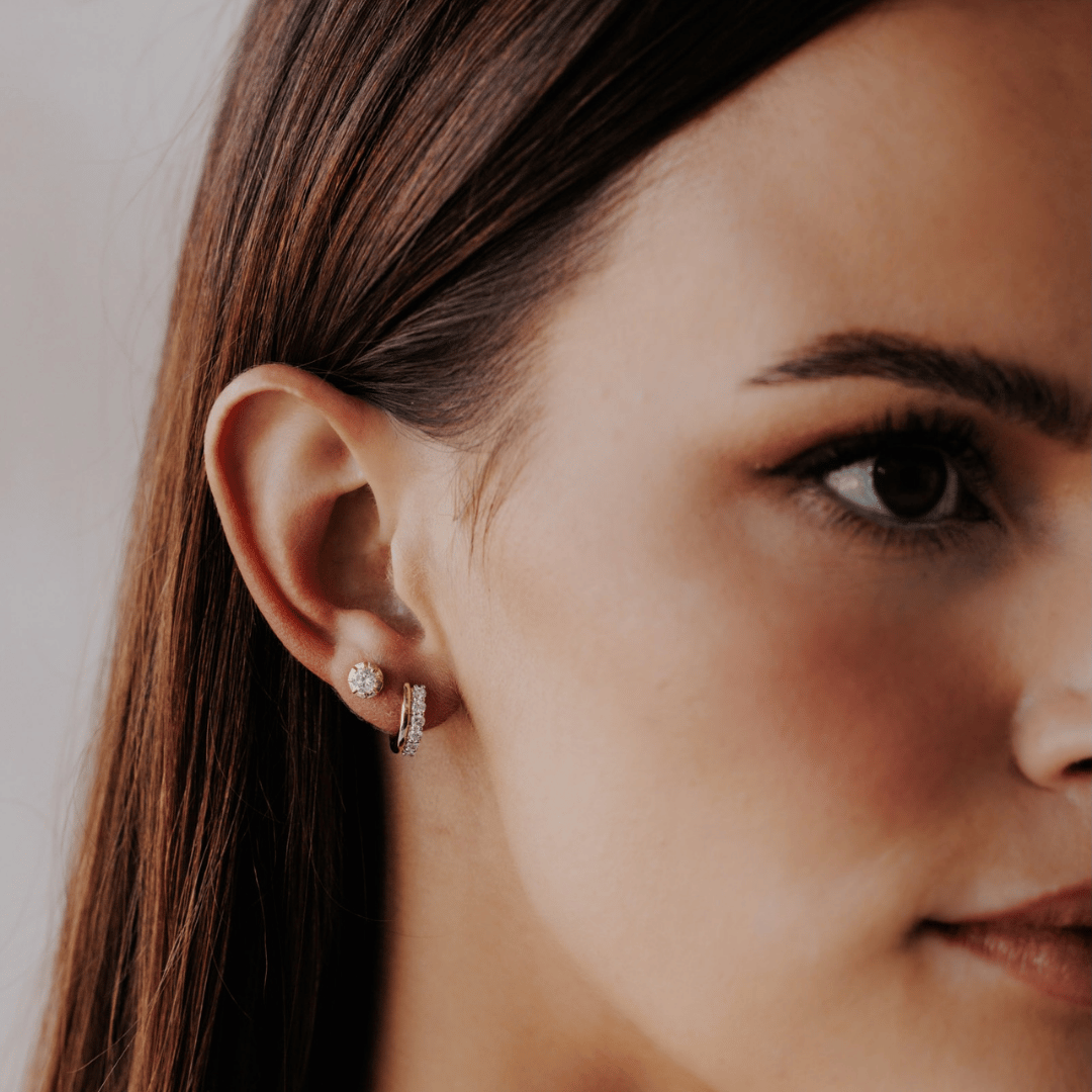 14k gold diamond huggie and plain huggie earrings showcased on a the ear of a model. 