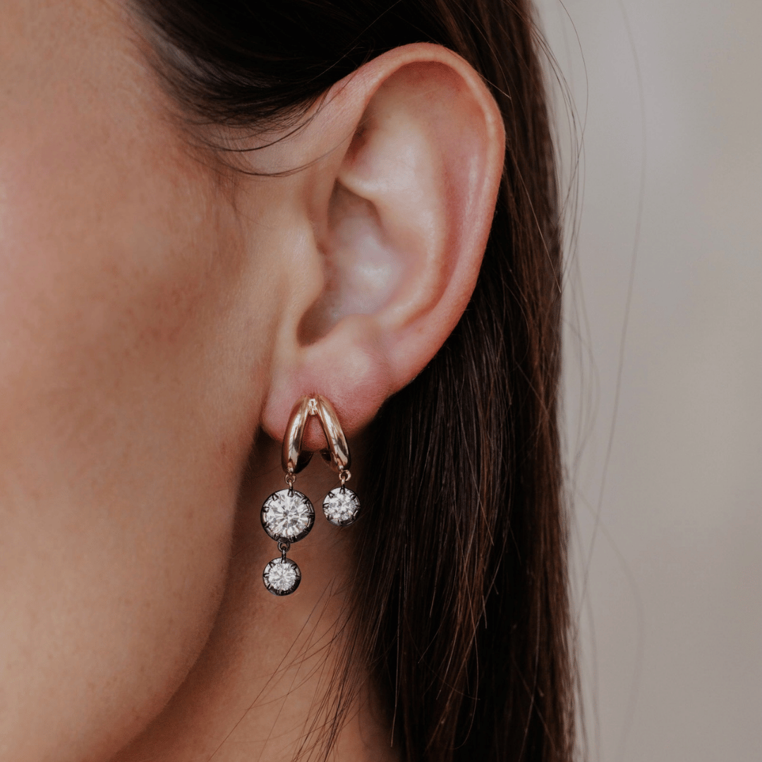 14k gold double hoop, round cut, lab grown diamond dangle earrings with Black Rhodium featured on the ear of a model. 