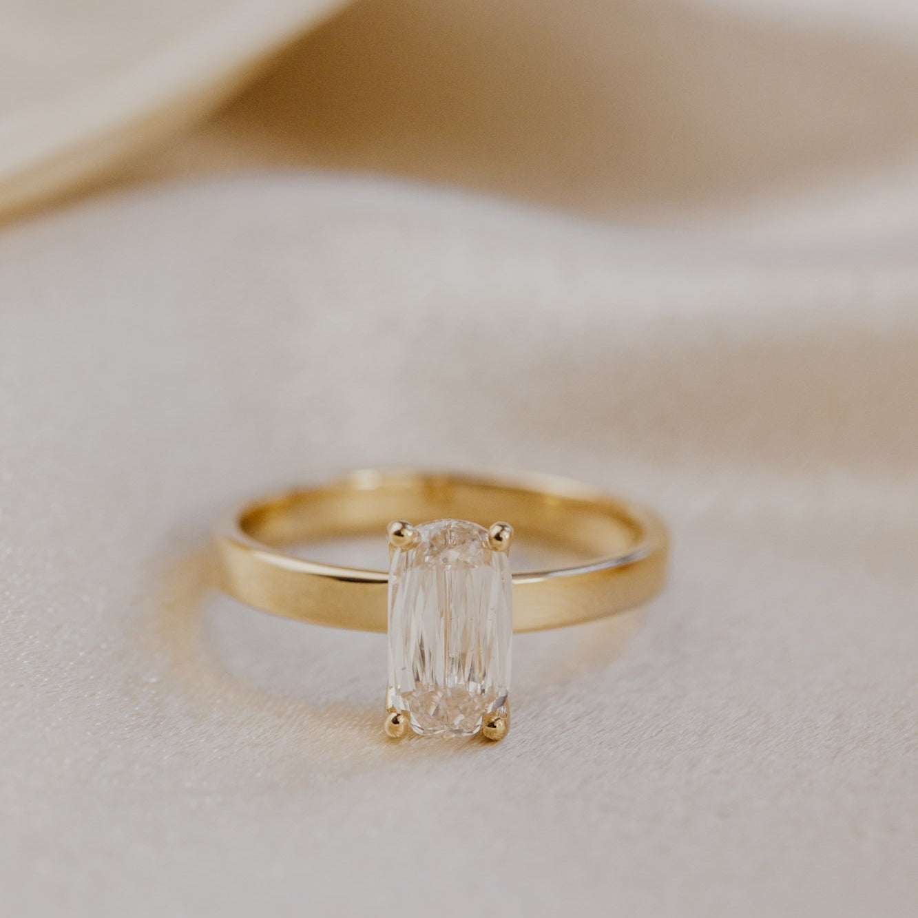 Gold ring with a champagne diamond on a soft beige background.